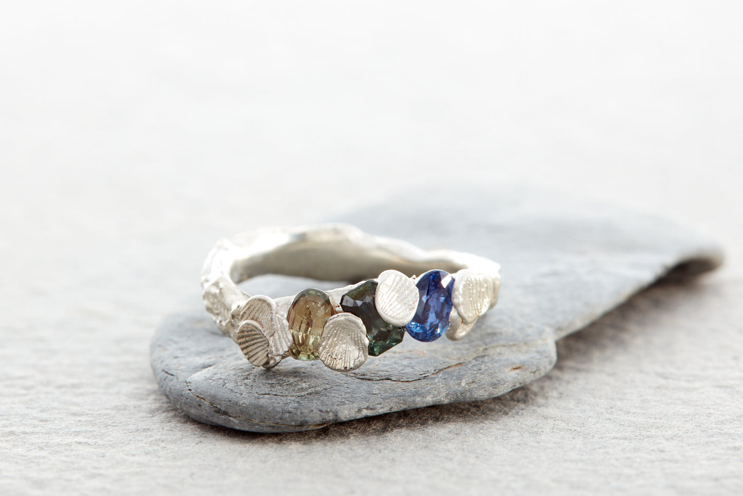 Sculptural silver Shellscape ring with organic coastal texture inspired by Devon shores and multicolour blue, teal and green sapphires.