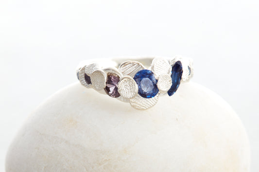 Handcrafted Shellscape Tidepool ring in recycled silver with blue sapphires and reddish brown sapphire inspired by North Devon coastline