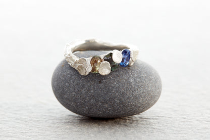 Sculptural silver Shellscape ring formed with organic textures inspired by the Devon coastline, set with ocean-toned sapphires in blue, teal and green.