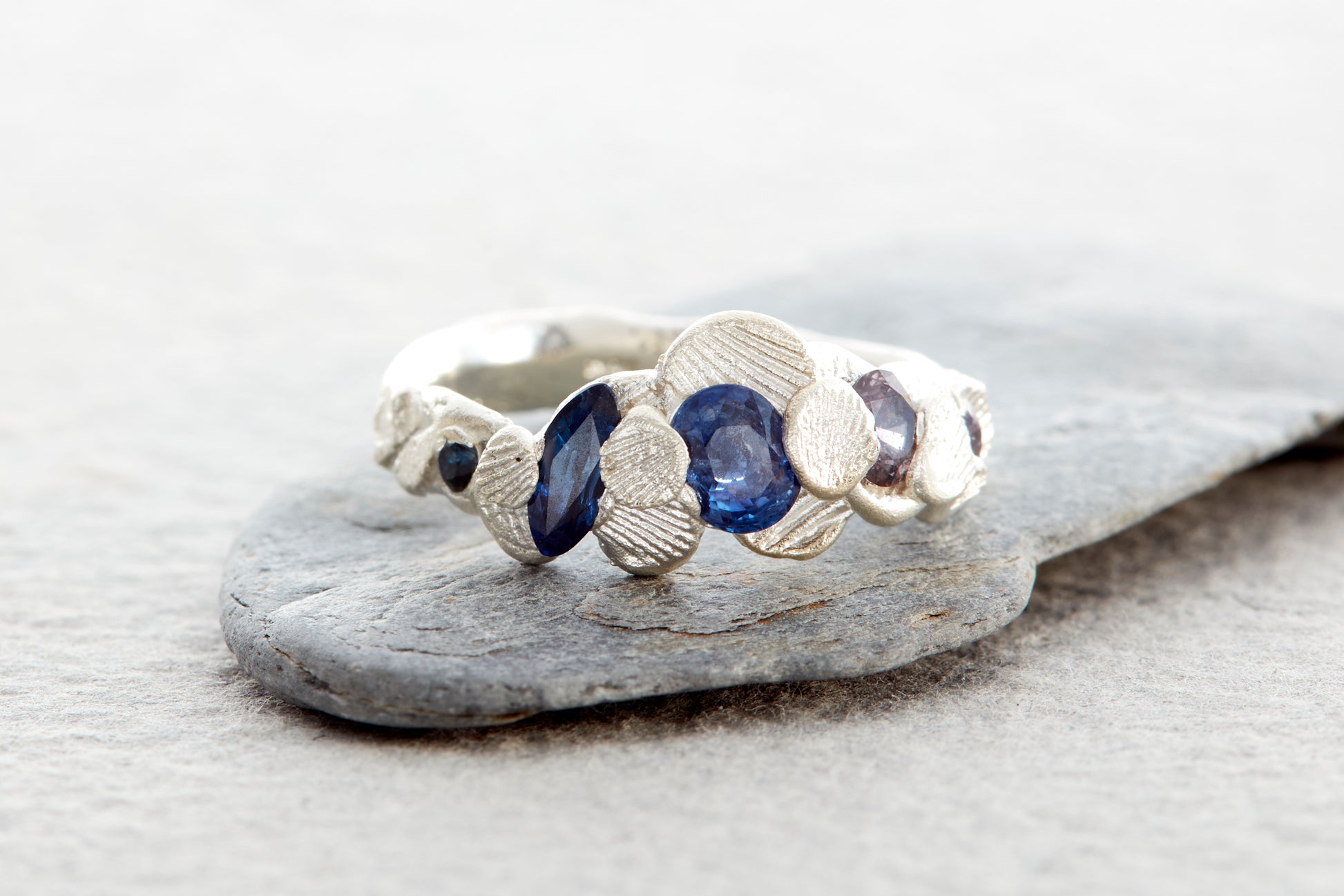 Sculptural silver ring with organic shell textures and ocean inspired gemstones in blue teal and earthy tones